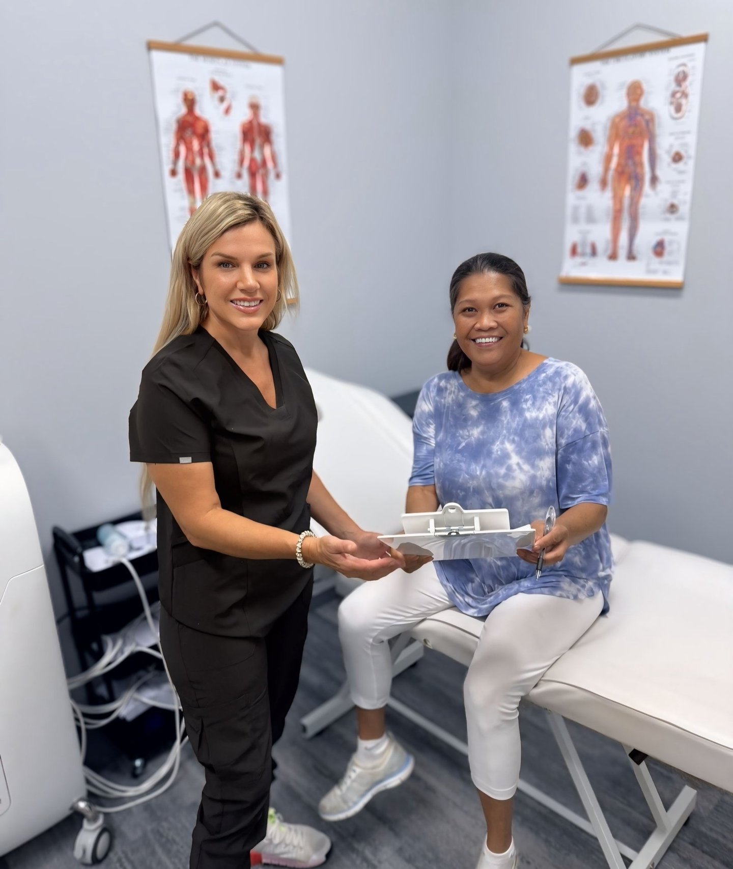 A Made Ya Skinny team member in scrubs handing a patient her paperwork in the treatment room