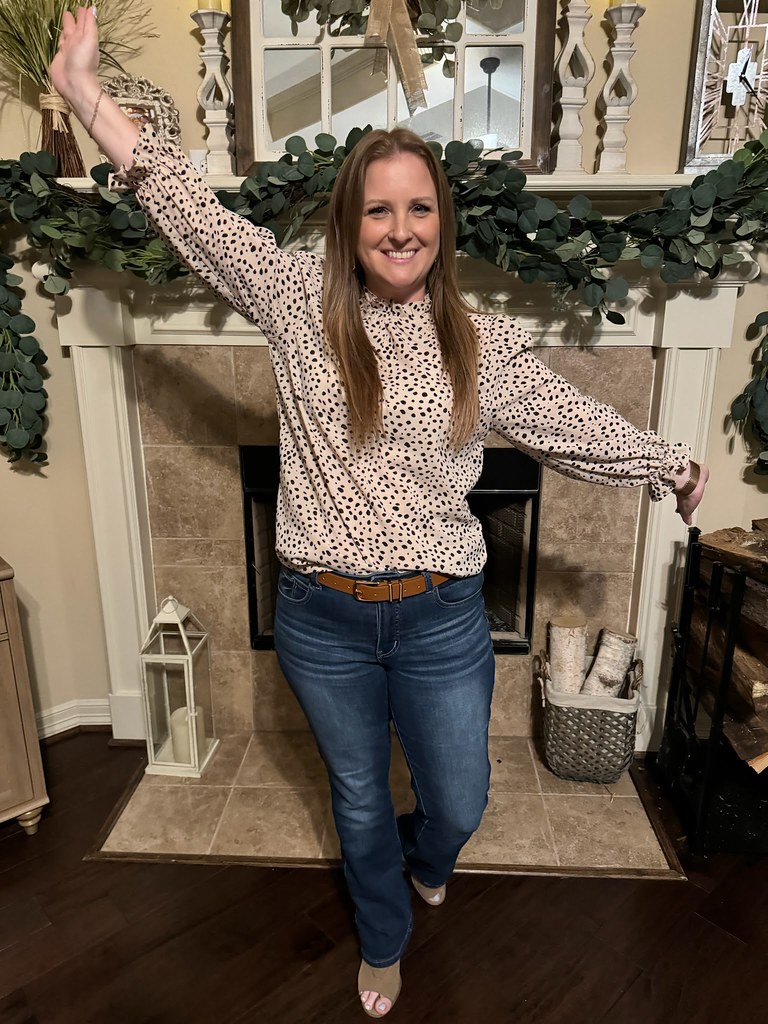 A woman standing with her arms out in front of a fireplace, after her weight management program