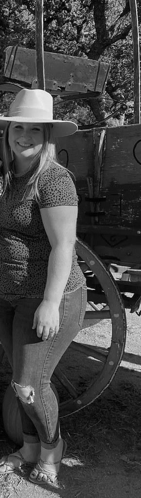 A woman standing beside an antique wagon wheel, before her weight management program